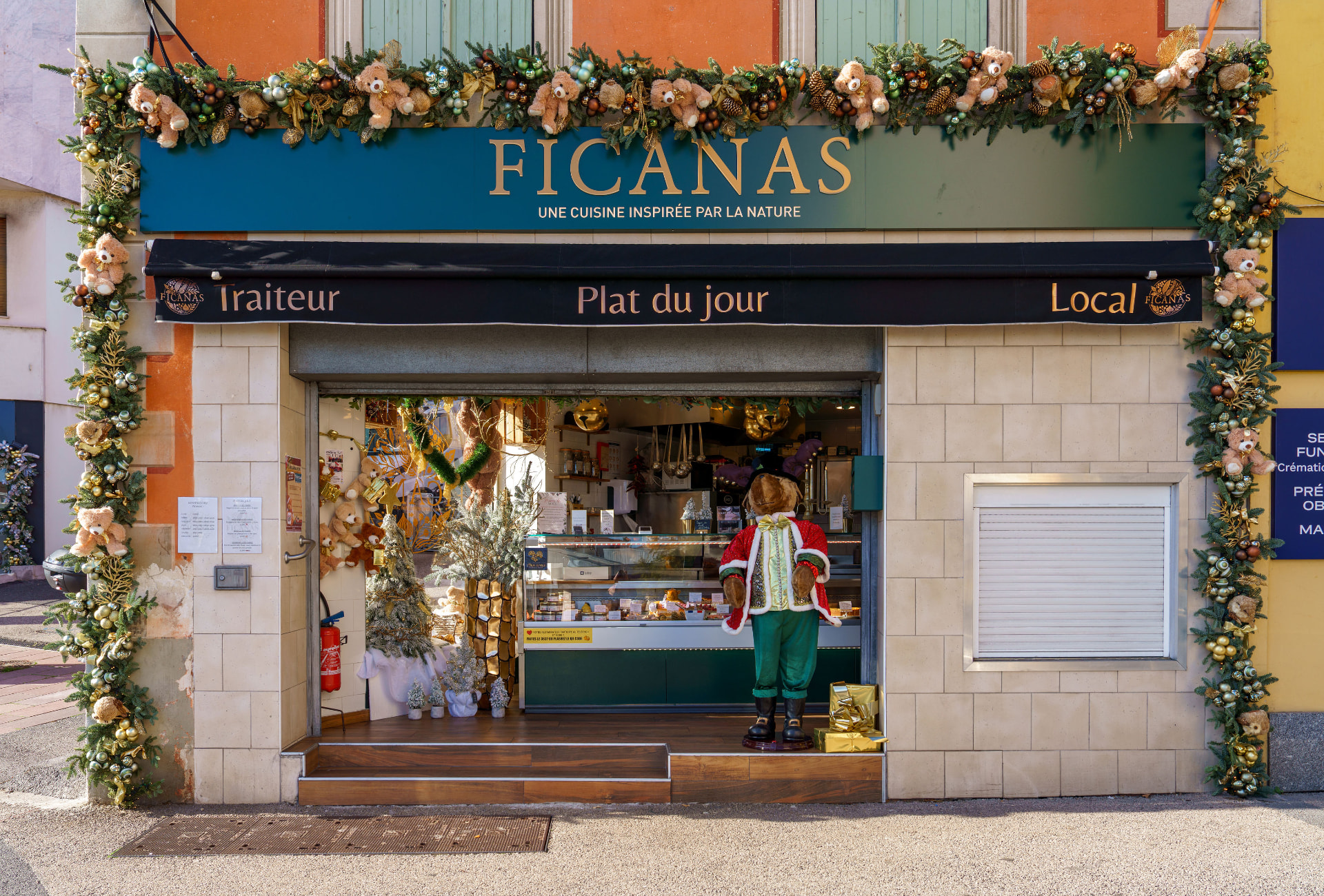 Devanture du traiteur Ficanas décorée pour Noël d'une guirlande de sapin, boules dorées et oursons